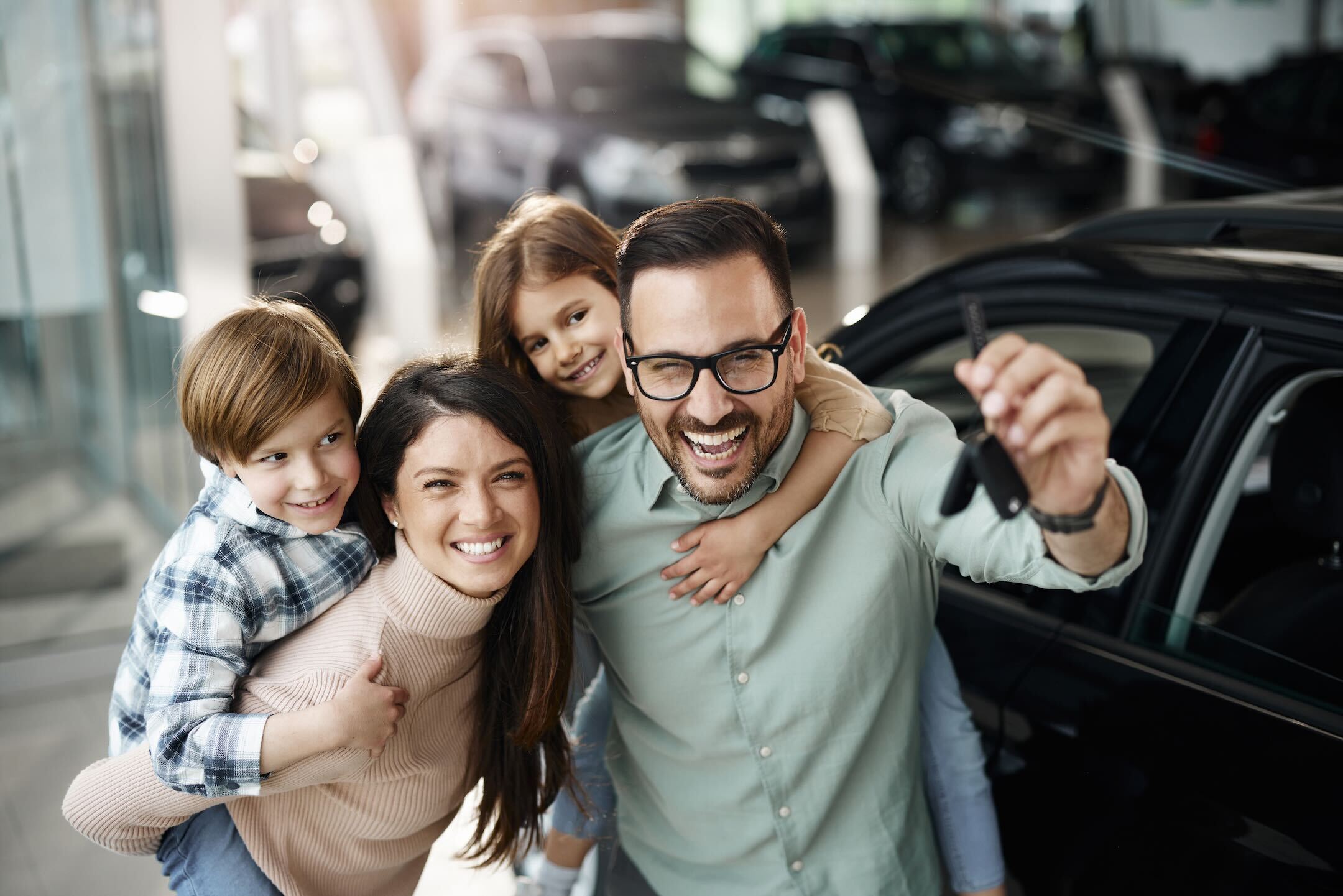 A family is standing in front of their new car showcasing how easy their car loan pre approval was to obtain.