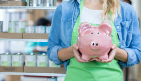 A woman is holding a piggy bank to emphasize SMART Financial Goals.