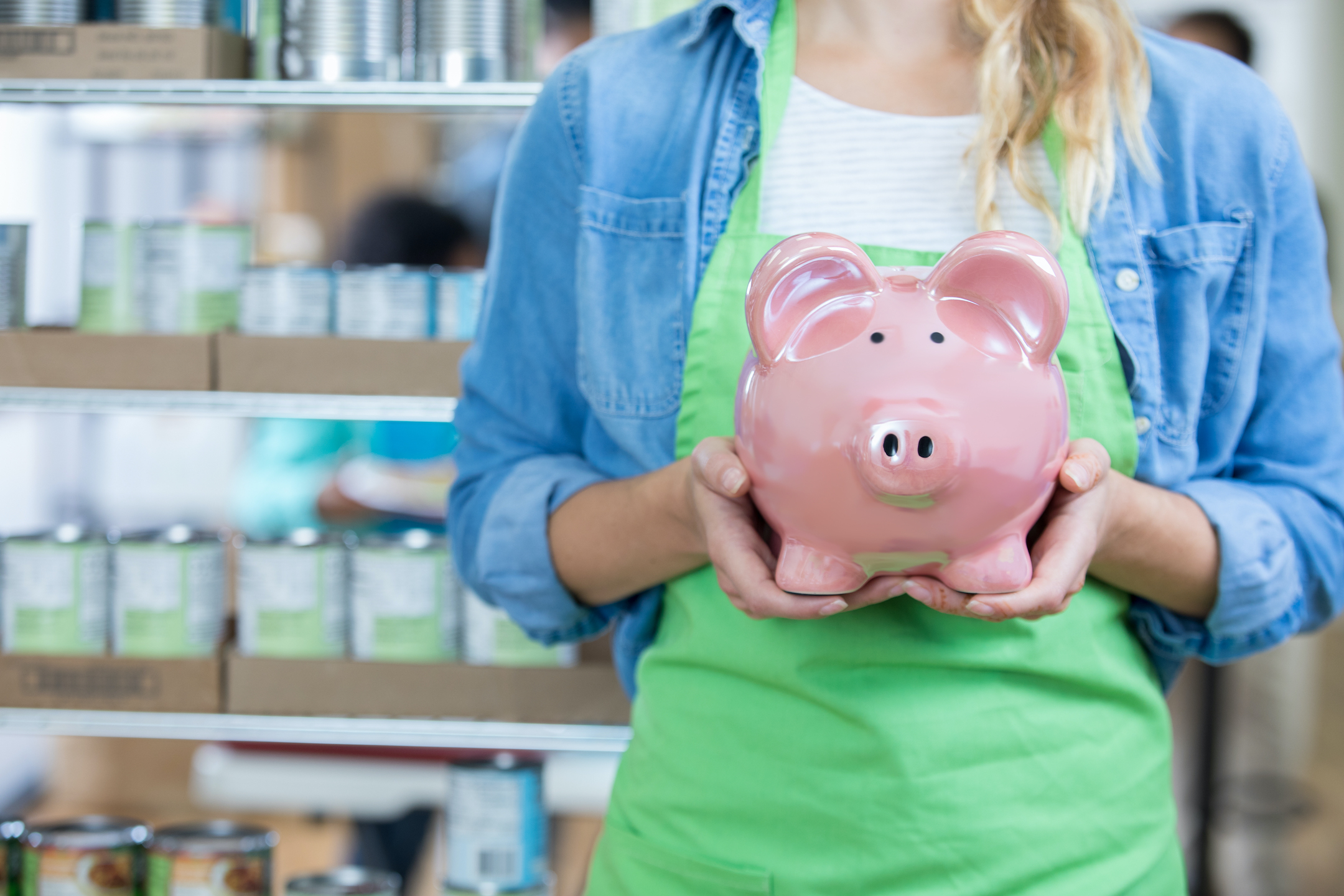 A woman is holding a piggy bank to emphasize SMART Financial Goals.
